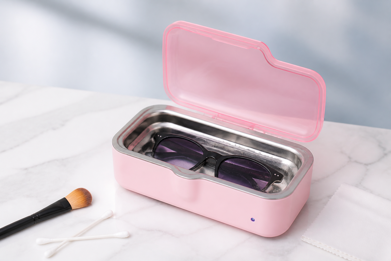 Pink compact ultrasonic eyeglass cleaner loosening residue from immersed glasses