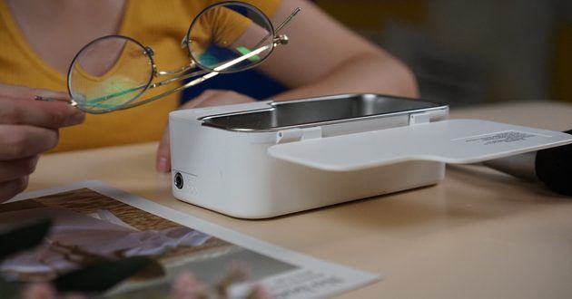White GT SONIC ultrasonic glasses cleaner on a desk with eyeglasses